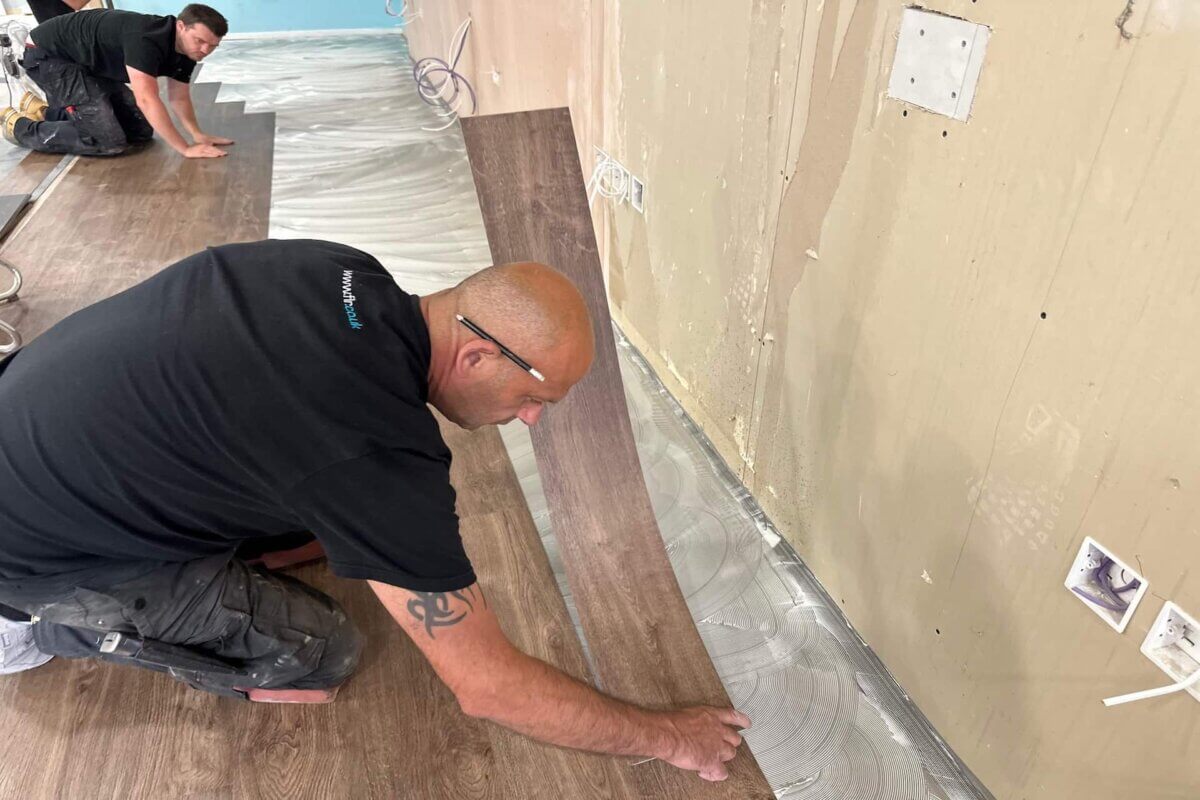 Senior fitter installing vinyl tile at opticians